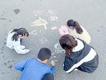 屋外で子どもたちが一緒にお絵かきを楽しんでいる様子